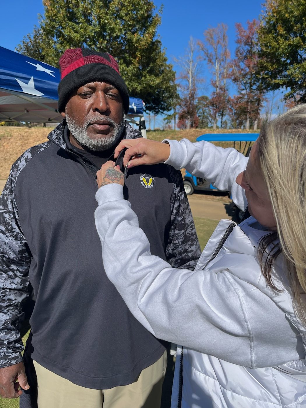A volunteer pinning a memorial ribbon on a supporter's jacket