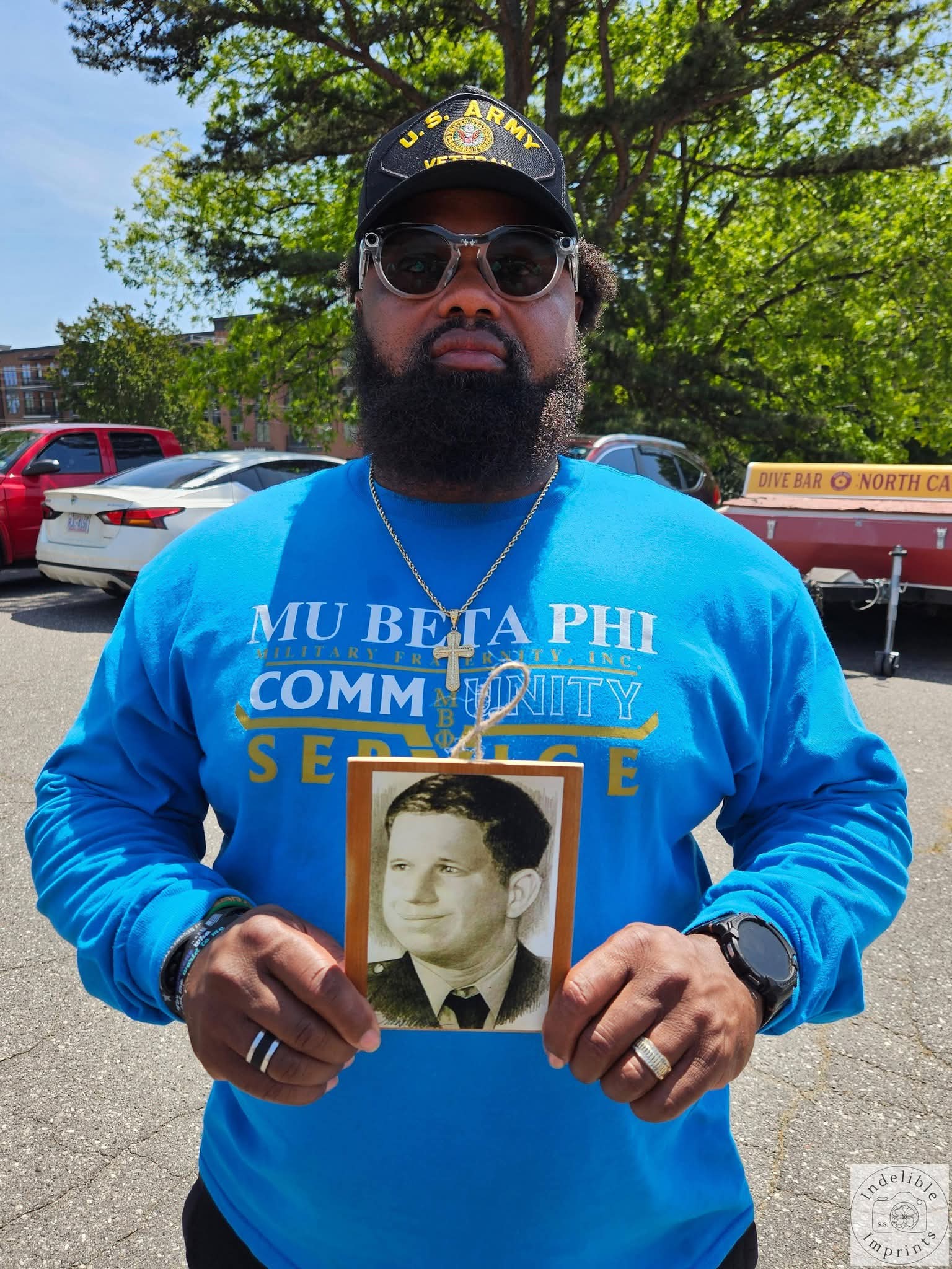 A Mu Beta Phi Military Fraternity member holding a memorial photo of a fallen veteran
